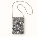Silver sequin crossbody bag with rhinestone strap on warm ivory background