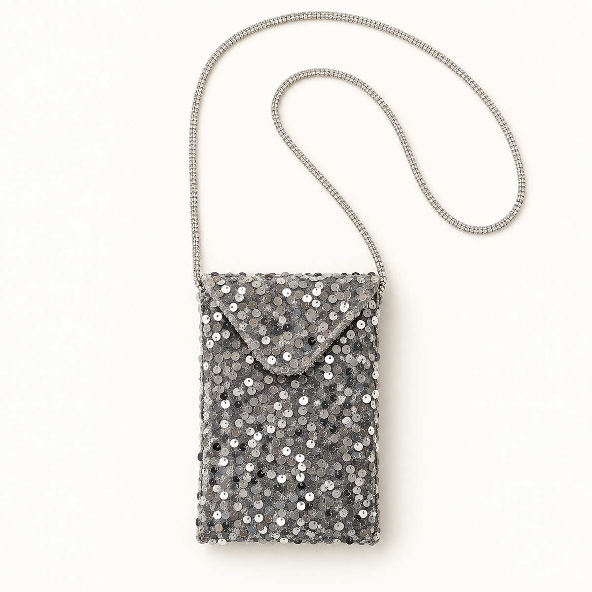 Silver sequin crossbody bag with rhinestone strap on warm ivory background