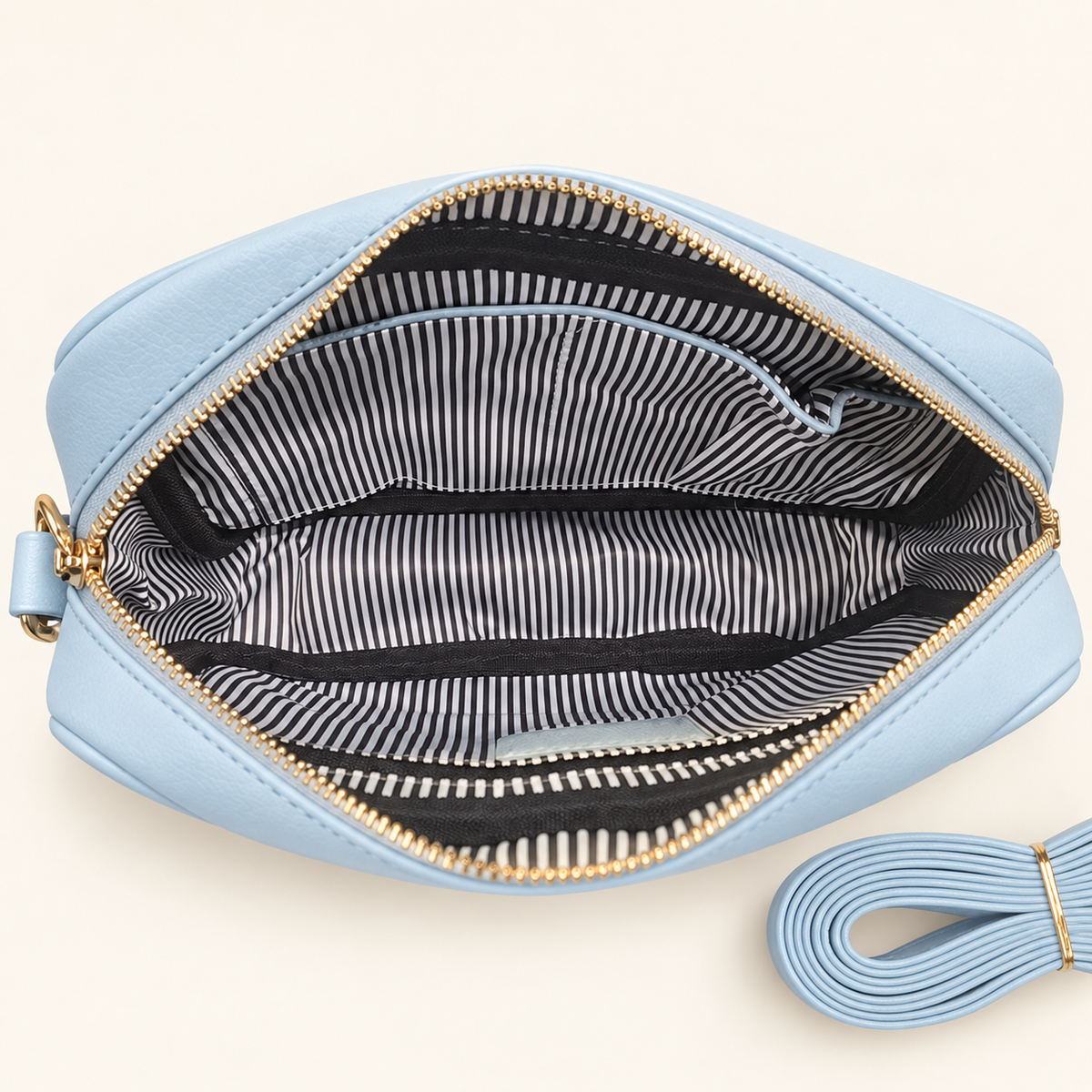 Inside the Blue Maisie bag showing black-and-white striped lining, interior pockets and matching narrow strap